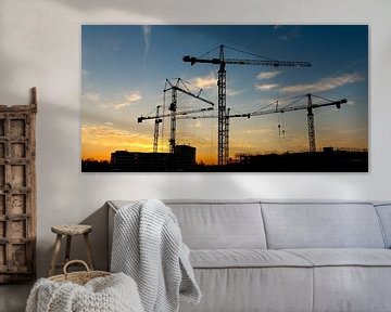 Construction site with cranes at sunrise by Marcel van den Bos