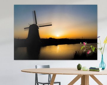 Silhouet van molen aan het water bij ondergaande zon van Sander de Vries