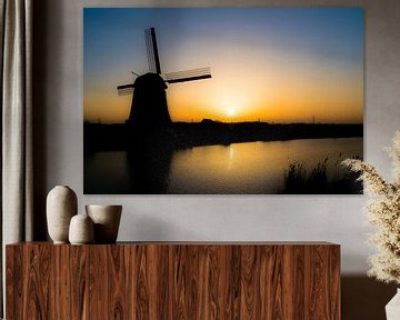 Silhouet van molen aan het water bij ondergaande zon van Sander de Vries