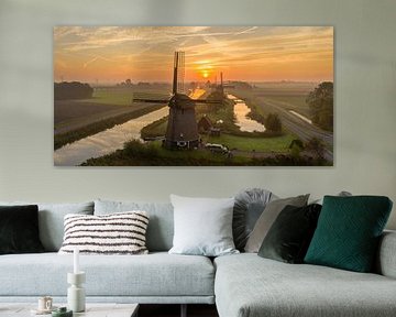 Typical Dutch windmill during sunrise sur Menno Schaefer