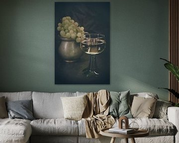 Ein Glas Weißwein mit hellen Weintrauben im Hintergrund