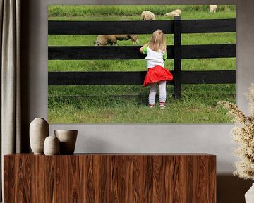 Meisje kijkt naar schapen door een hek van Mathieu van den Berk