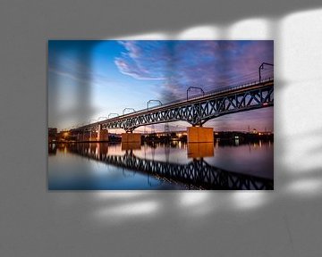 Treinbrug visé bij de Maas rivier - zonsondergang met spiegeling blauwe lucht bij spoorbrug