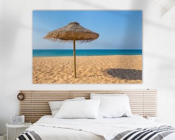 Rieten parasol op portugees strand met blauwe zee van Ben Schonewille