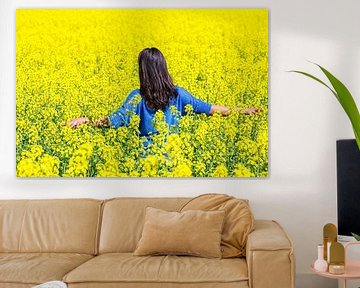 Young colombian woman walking in field with yellow rapeseed flowers sur Ben Schonewille