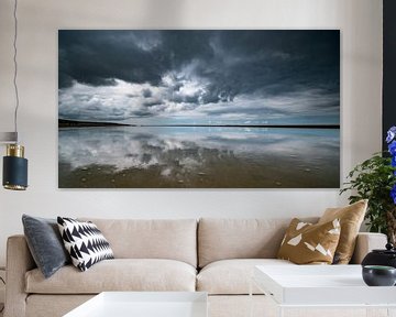 Stormy skies with reflections on the sand by Remco Piet