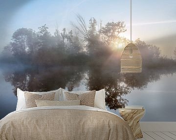 Zonsopkomst in de mist door de bomen met een waterreflectie