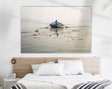 A man with a wooden boat is rowing the sacred Ganges River in Gosaba, West Bengal, India. by Tjeerd Kruse