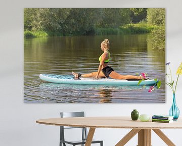 Young european woman in yoga posture on SUP in water