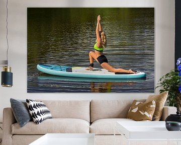 Jonge vrouw oefent yoga op SUP of paddle board op water in natuur