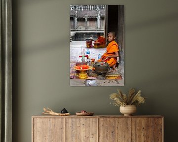 Monnik (kind) in oranje pij en offeranden bij Angkor Wat