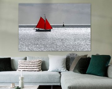 Zeilbootje met rood zeil tegen de schittering van de zon op de Waddenzee nabij het eiland Terschelli