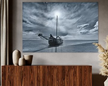 Black-and-white photo of a dry-fall sailing ship on a sandbank in the Wadden Sea