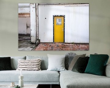 Yellow door in black frame of white building by Idema Media