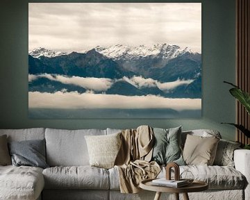 Wolken tussen de besneeuwde bergtoppen. van Idema Media