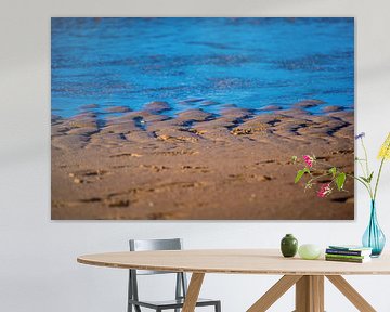 Blaue Wellen an einem braunen Strand