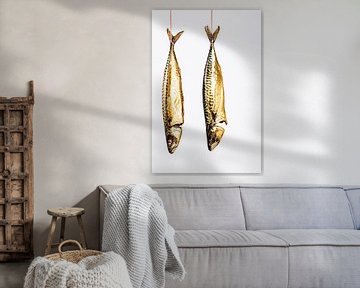 twee makrelen hangen aan een stuk rood-wit keukentouw tegen een witte achtergrond. van MICHEL WETTSTEIN