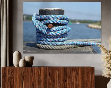 Roestige bolder met blauw scheepstouw aan het water van Maarten Pietersma