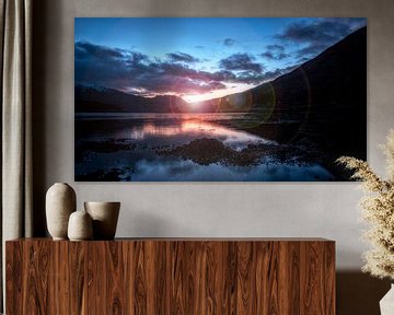 the last ray of sunshine of the day across the windless lake in Scotland by Hans de Waay