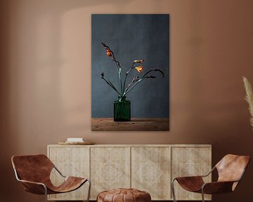 Foto print van oranje bloem in groene glazen vaas tegen een blauwe achtergrond van Jenneke Boeijink