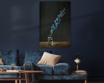 Foto print van blauwe bloem in glazen vaasje tegen grijze achtergrond van Jenneke Boeijink