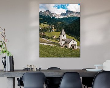 Kirche in den italienischen Dolomiten mit den schroffen Bergen in den Wolken im Hintergrund.