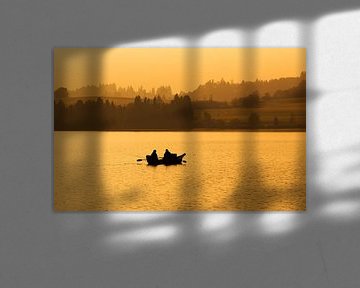 Deux pêcheurs dans un bateau à rames sur le lac au coucher du soleil