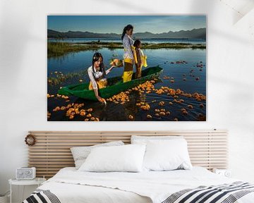 Young girls sacrifice orange flowers on Lake Batur in Bali, Indonesia by Anges van der Logt