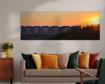Zonsondergang aan Belgische kust, strandhuisjes en duinen.