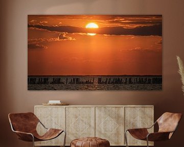 Zonsondergang Waddenzee met een mooie rij palen op de voorgrond. van Martijn van Dellen