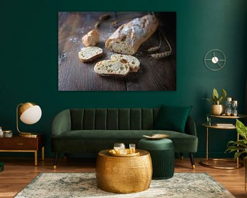 Fresh baguette or French bread baked with onions, half sliced, on dark rustic wood, selected focus,  by Maren Winter