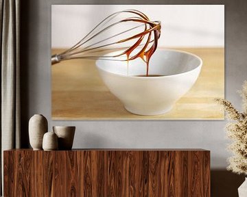 Bruine melasse stroomt van een draadklopper naar een witte kom, bakkend thuisconcept, houten tafel e van Maren Winter
