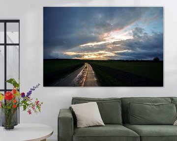 Wet reflecting country road made of concrete slabs is leading through the dark fields under a dramat by Maren Winter