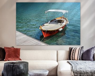 Rode houten boot met ligvlak en zonnescherm op de steiger in het turquoise water van de Middellandse van Maren Winter