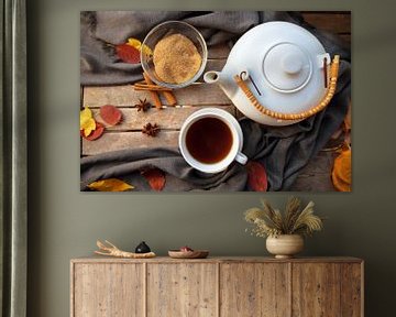 theekopje en een witte theepot op een houten tafel met specerijen en wat herfstbladeren, hoog hoekbe van Maren Winter