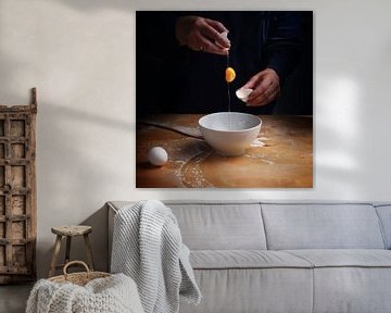 older women hands breaking an egg with falling egg yolk over a bowl, wooden kitchen board, dark back by Maren Winter
