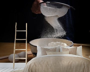 flour falling in a bow from a sieve into a bowl on a wooden kitchen worktop at baking preparation, d by Maren Winter