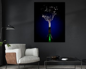 Champagnerflaschenexplosion mit korkspringendem Spritzer vor einem dunklen Hintergrund mit blauem bi von Maren Winter