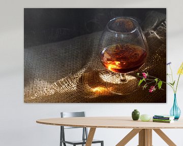 Cognac of brandewijn in een glas met een gloeiende lichtreflex op rustieke jute, concept voor genot  van Maren Winter
