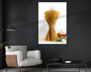 bosje volkoren spaghetti dat zich op wit hout bevindt met wat tomaten en kruiden die tegen een witte van Maren Winter