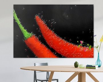 Rode paprika's staan onder water met luchtbellen tegen een zwarte achtergrond van Ulrike Leone