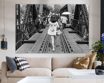 Woman walks across bridge in black and white by Bart van Lier