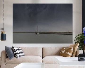 White flat-bottomed sails into the port of Harlingen and a dark sky by Harrie Muis