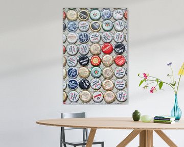 Varied collection beer bottle caps glued on a wall  by Tony Vingerhoets