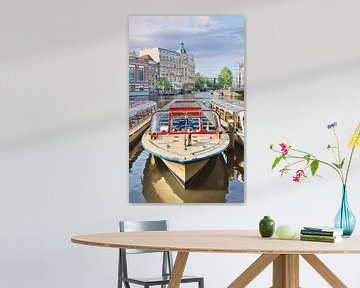 Retro stijl Tour boot met oude herenhuis in Amsterdam