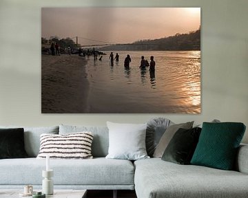 People take a bath in the sacred river Ganges in India at sunset by Eye on You