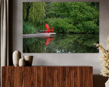 Une chaise de plage rouge se reflète dans l'eau lisse