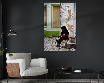 Une femme est assise devant sa maison sur Marieke van der Hoek-Vijfvinkel