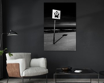Schwarz-Weiß-Bild eines Schildes mit einem Clown am Strand von Wim Stolwerk