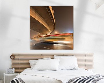 Elevated bending highway with bus in motion blur at nighttime by Tony Vingerhoets